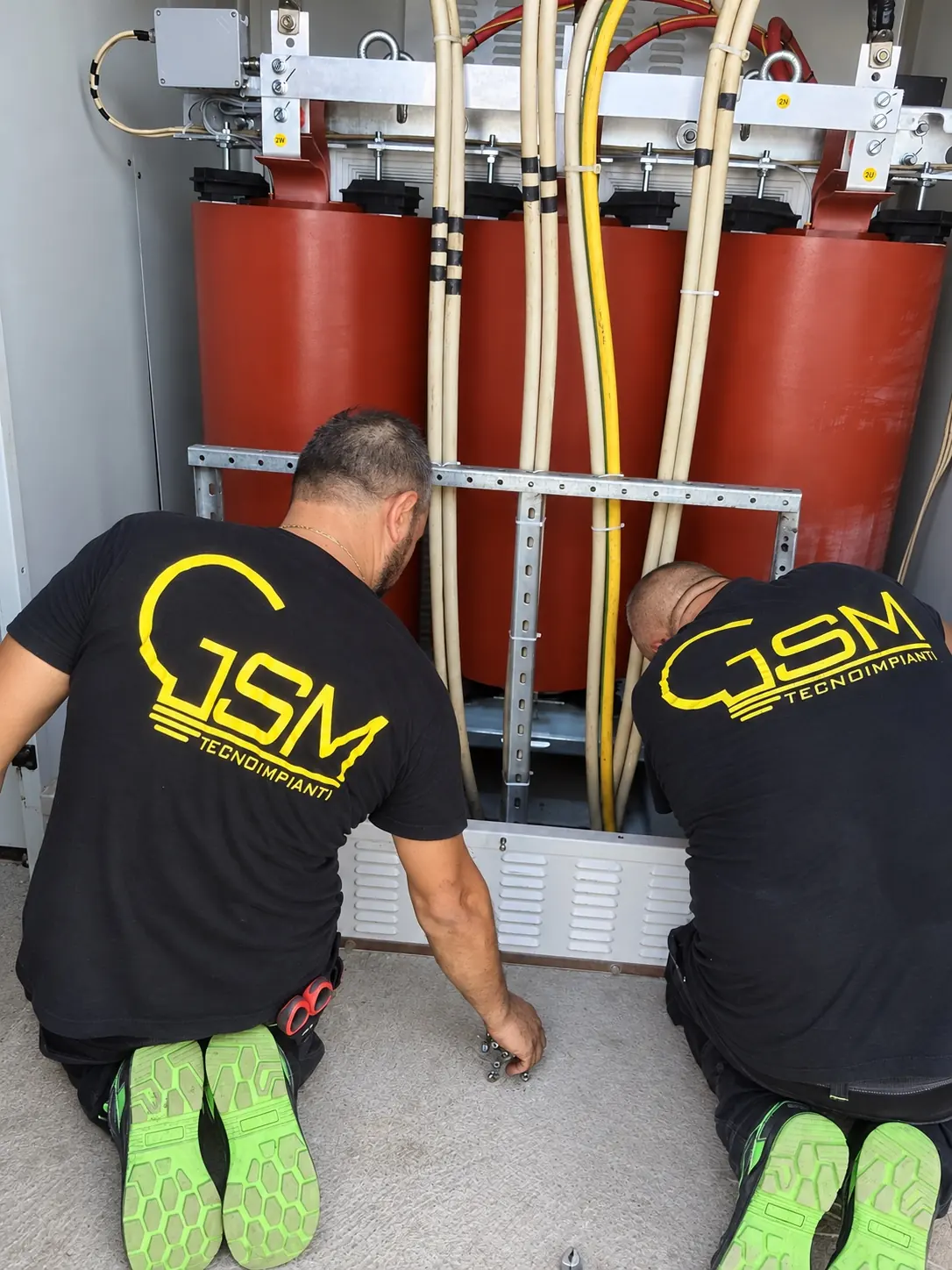 Due tecnici di G.S.M. Tecnoimpianti, in maglia col logo, al lavoro sul trasformatore di una cabina MT/BT
