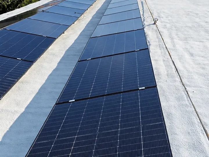 Una lunga fila di pannelli fotovoltaici sul tetto, col cielo azzurro