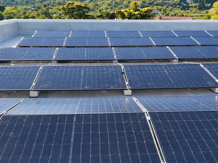 File parallele di pannelli fotovoltaici su un tetto piano, con le colline sullo sfondo