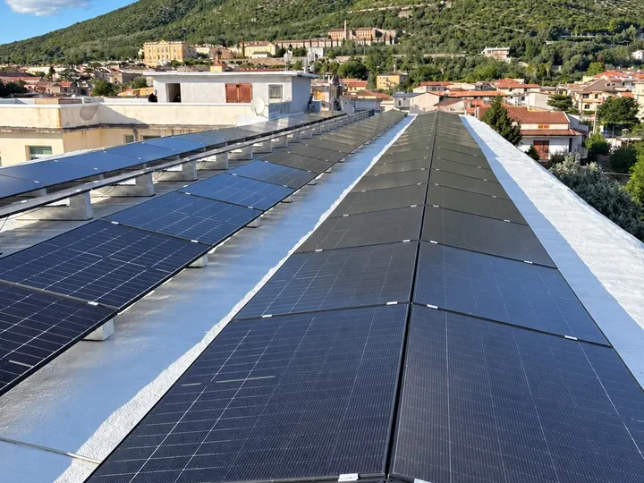 Pannelli fotovoltaici su un tetto piano, con la montagna e il paese sullo sfondo
