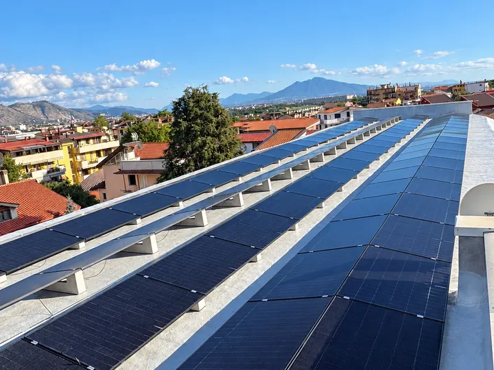 Pannelli fotovoltaici sul tetto, coi monti e il paese sullo sfondo