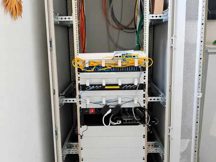 Un armadio rack completo in un ufficio, con switch, fibra e gruppo di continuità